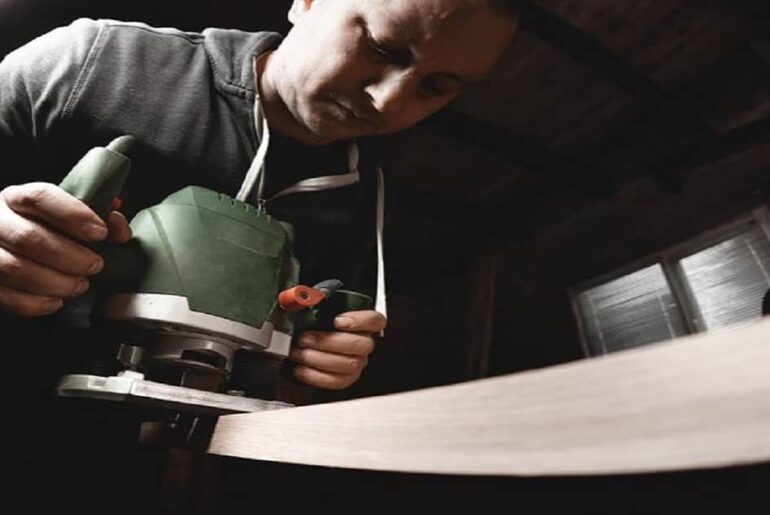 Carpenter with hand electric Compact router machine at work